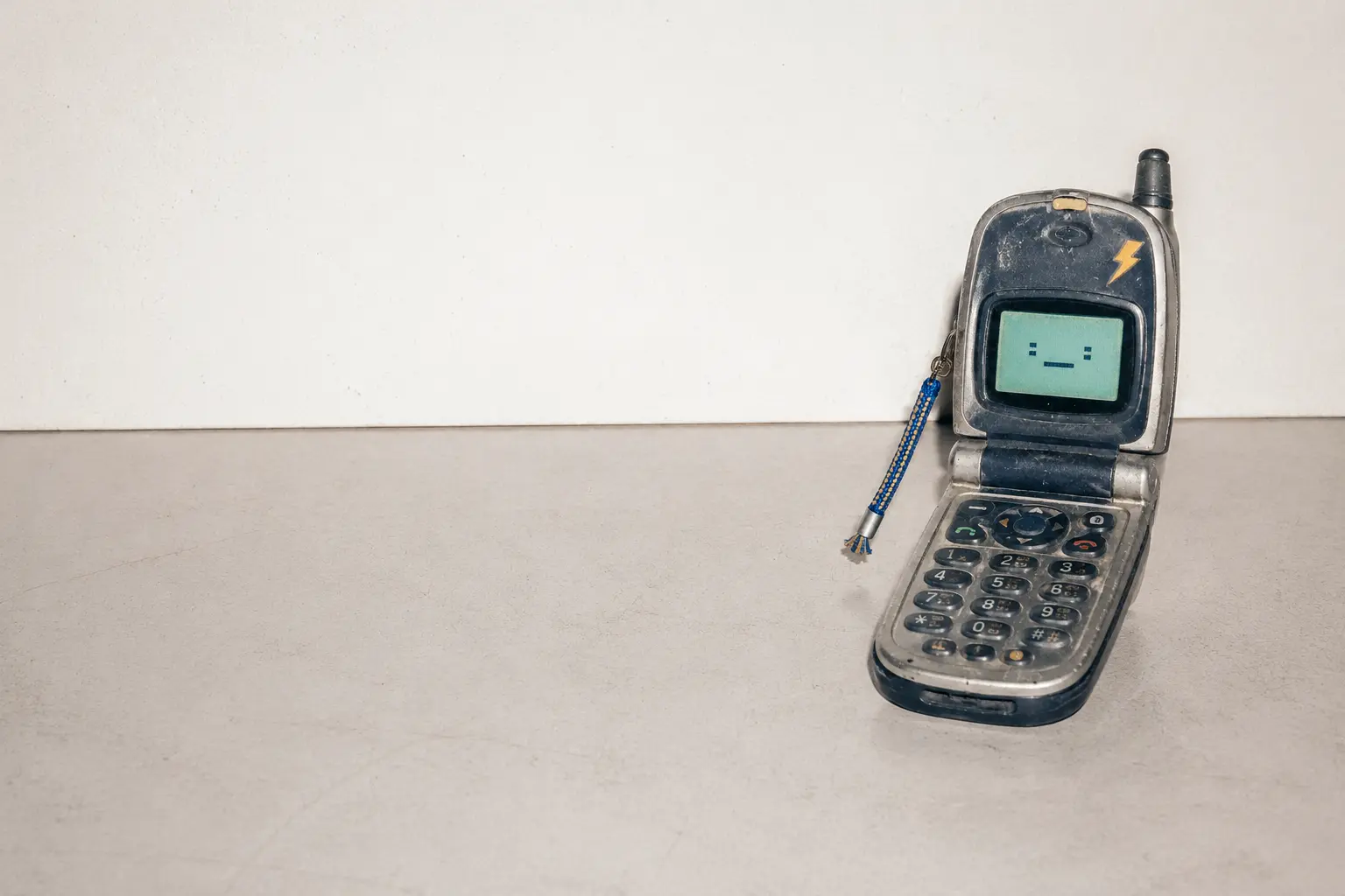 Clacky, a battered navy and silver flip phone, open on a quiet desk.