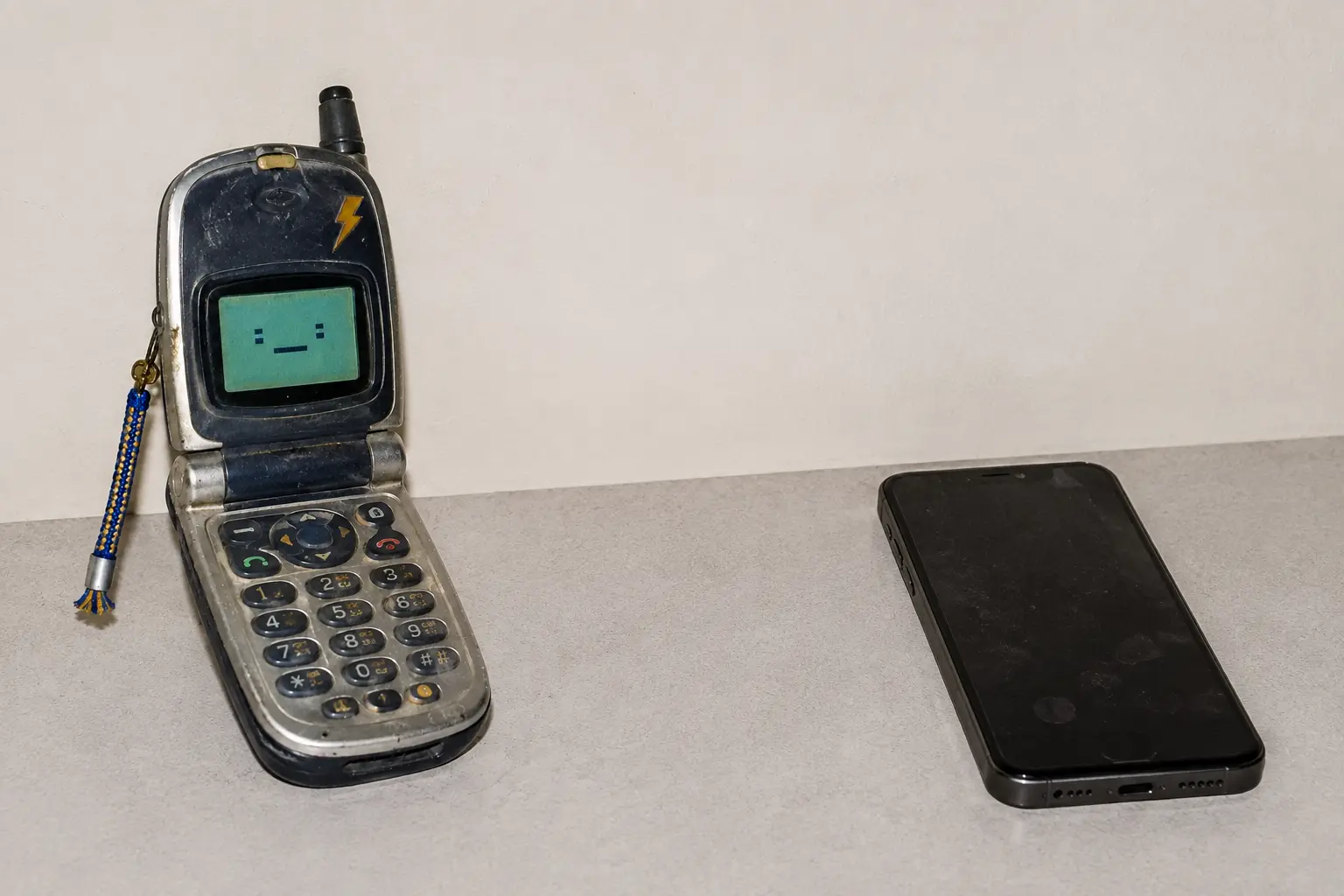 Clacky facing a modern black smartphone across an empty desk.